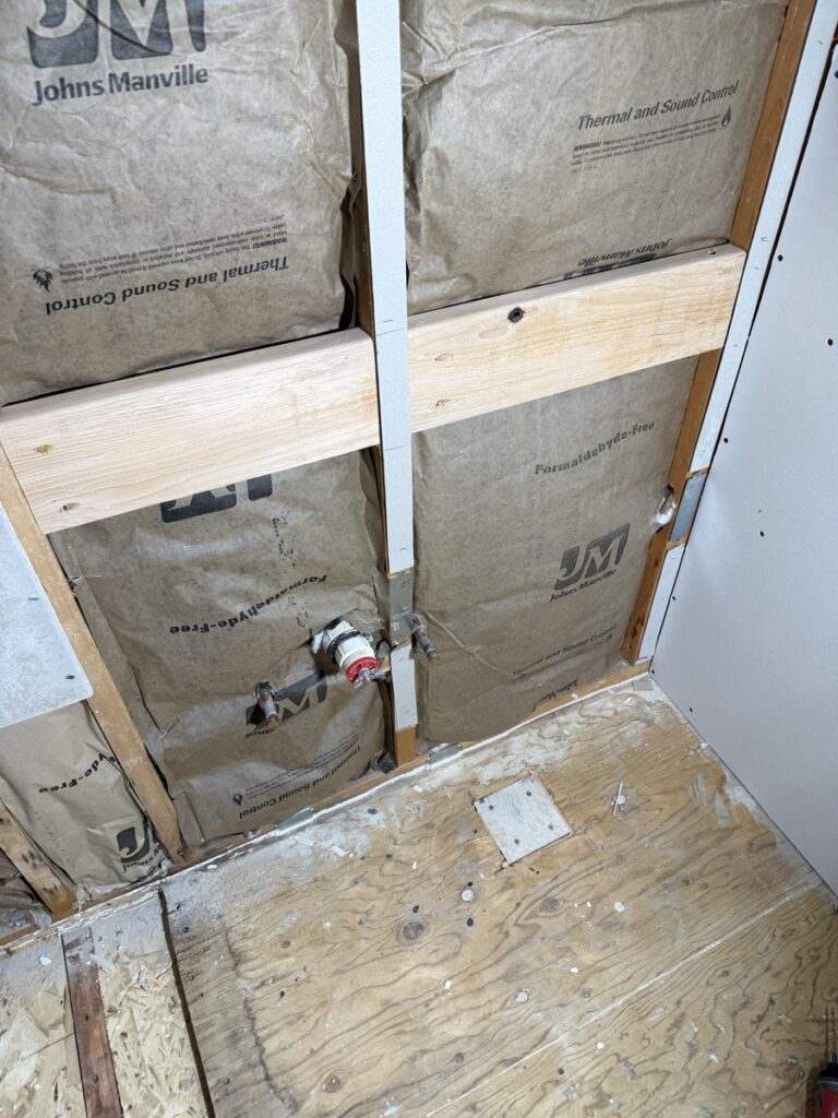 Bathroom stripped to studs during demolition with Johns Manville thermal and sound insulation and new plumbing rough-in