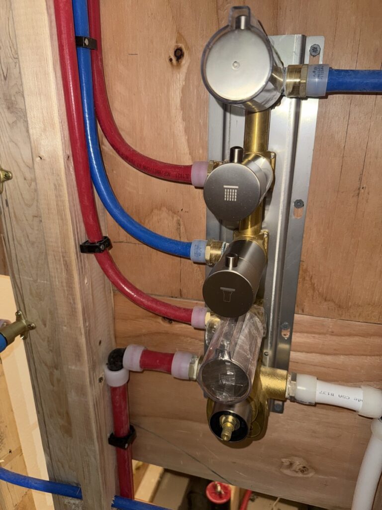 Shower valve rough-in with brass body, PEX supply lines and drop ears mounted to wood blocking