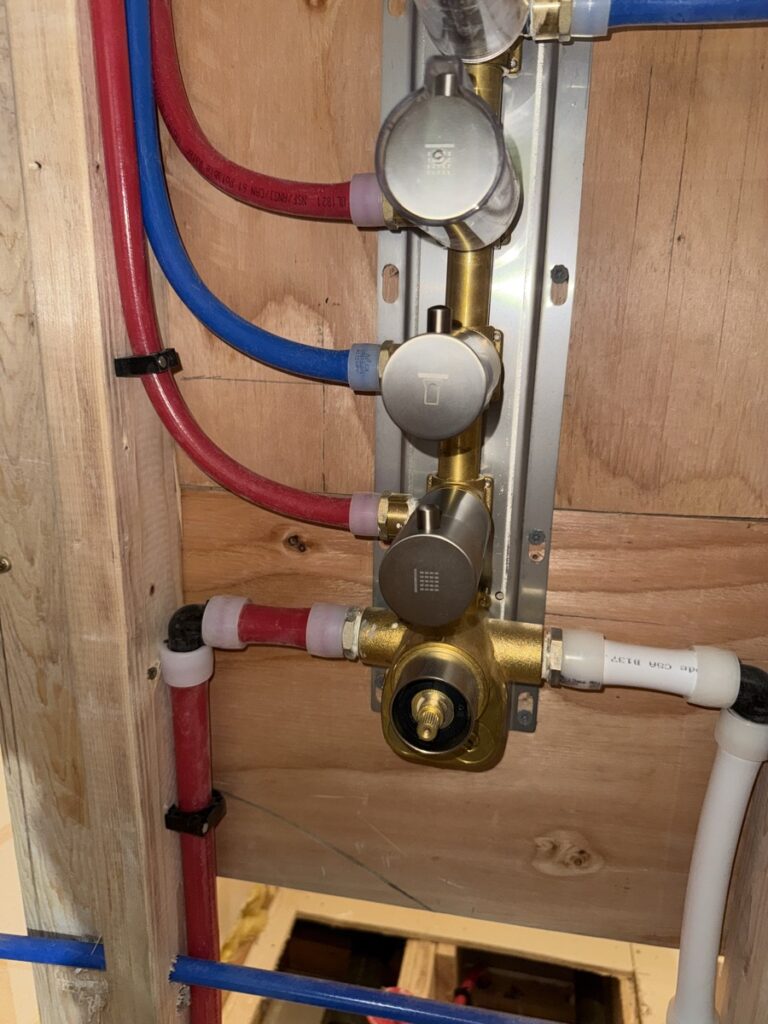 Close-up of a shower valve rough-in plate with hot, cold and diverter ports ready for trim