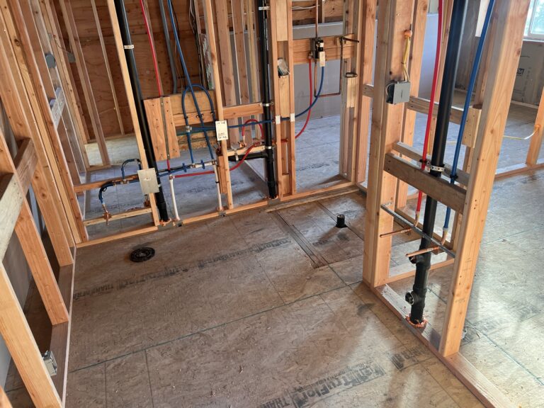 New bathroom plumbing rough-in with PEX supply lines, copper, and ABS drain stacks in open stud walls
