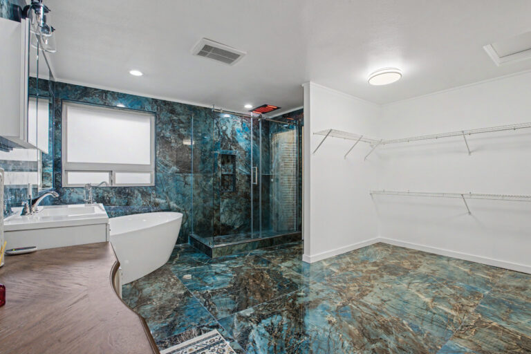 Luxury master bathroom remodel with blue quartzite slab walls, freestanding soaking tub and glass walk-in shower